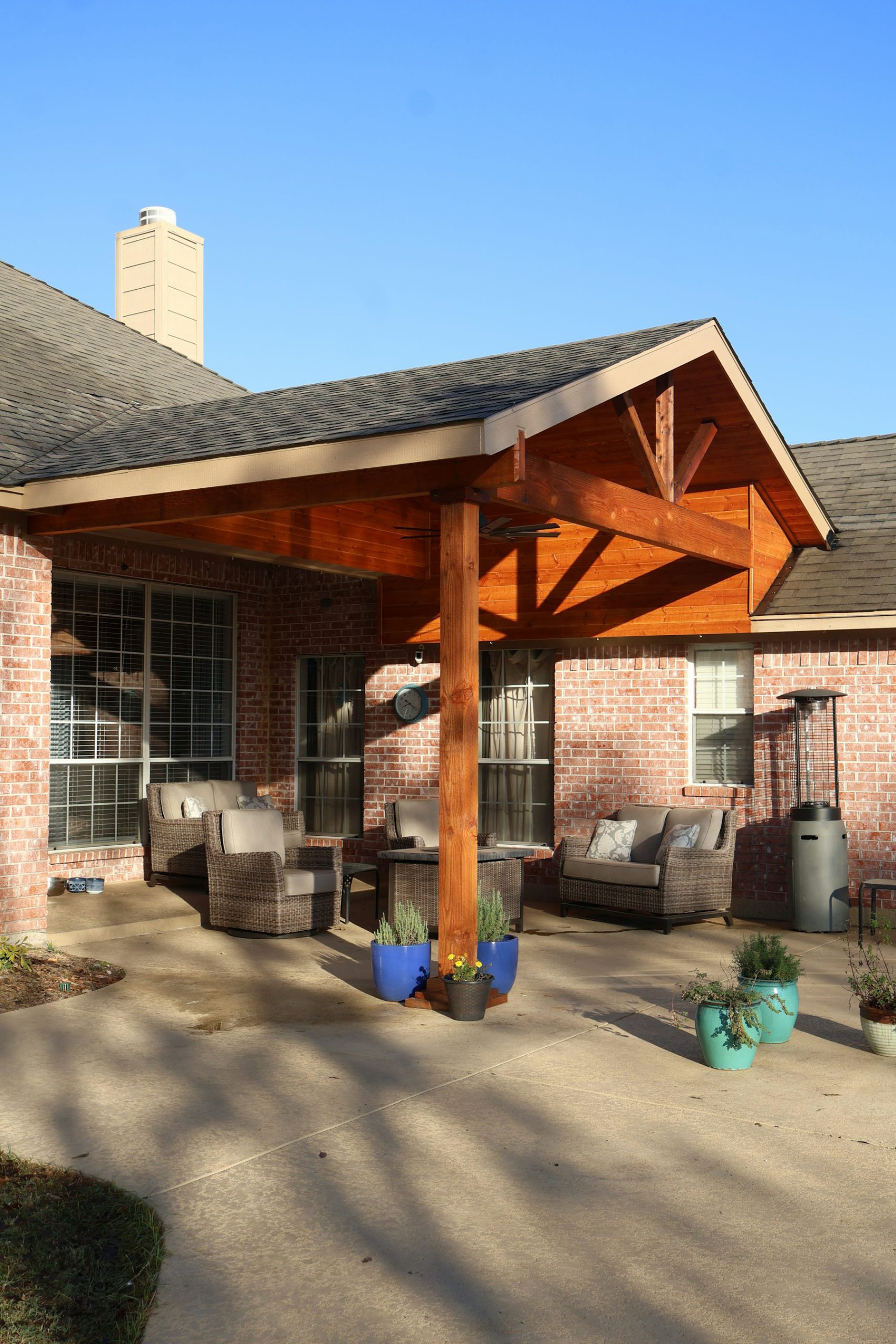 Timber-framed covered patio addition on a brick home with outdoor seating