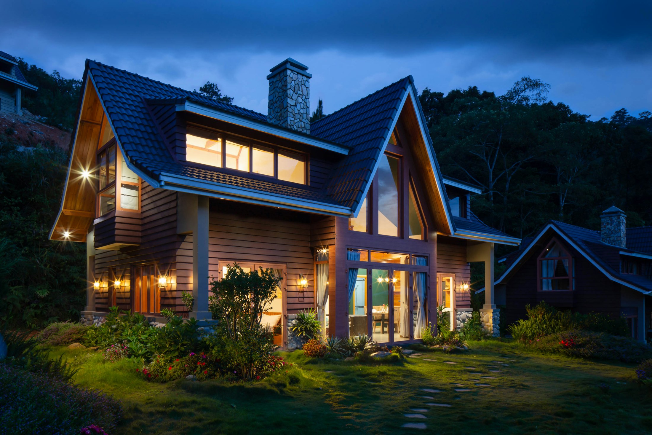 Craftsman-style custom home with steep gables and glowing windows at dusk