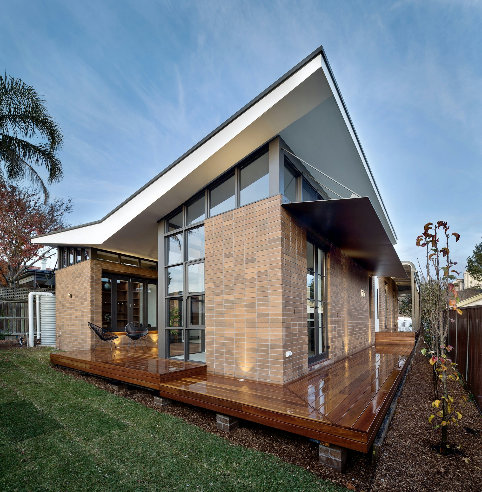 Modern home addition with a shed roof, tall glass walls and a wraparound wood deck