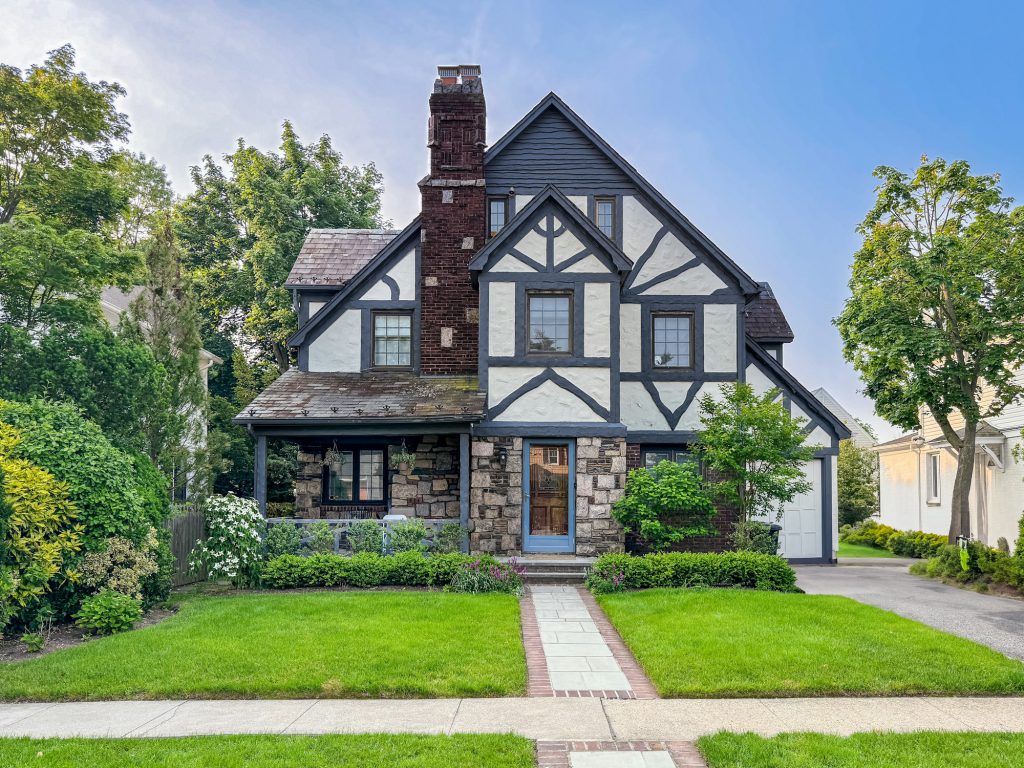 Tudor-style home with half-timbered gables, a stone base and a brick chimney