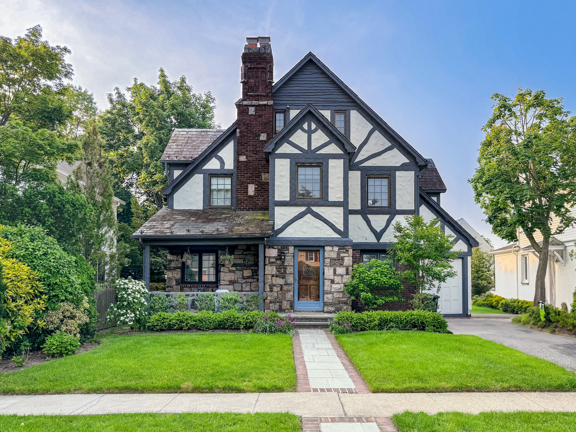 Tudor-style home with half-timbered gables, a stone base and a brick chimney